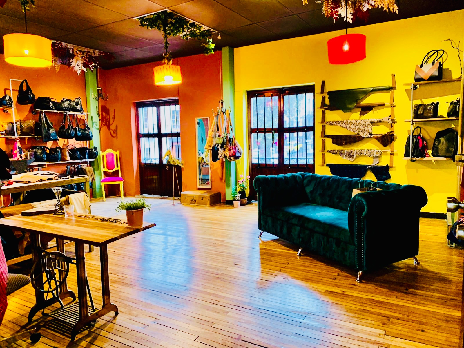 The Auka Style workshop in Quito, Ecuador — bags on display, leather swatches, teal velvet sofa